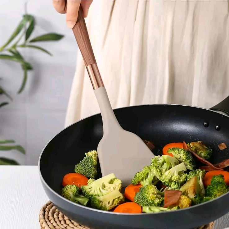 Espátula de silicone bege em uso mexendo legumes na frigideira